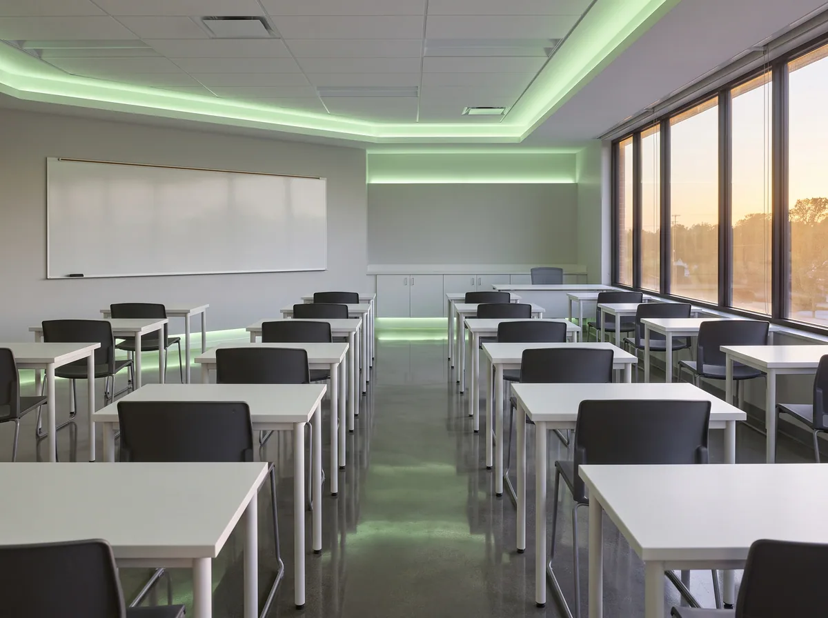 An empty classroom at night with desks aligned and a freshly mopped, shining floor.